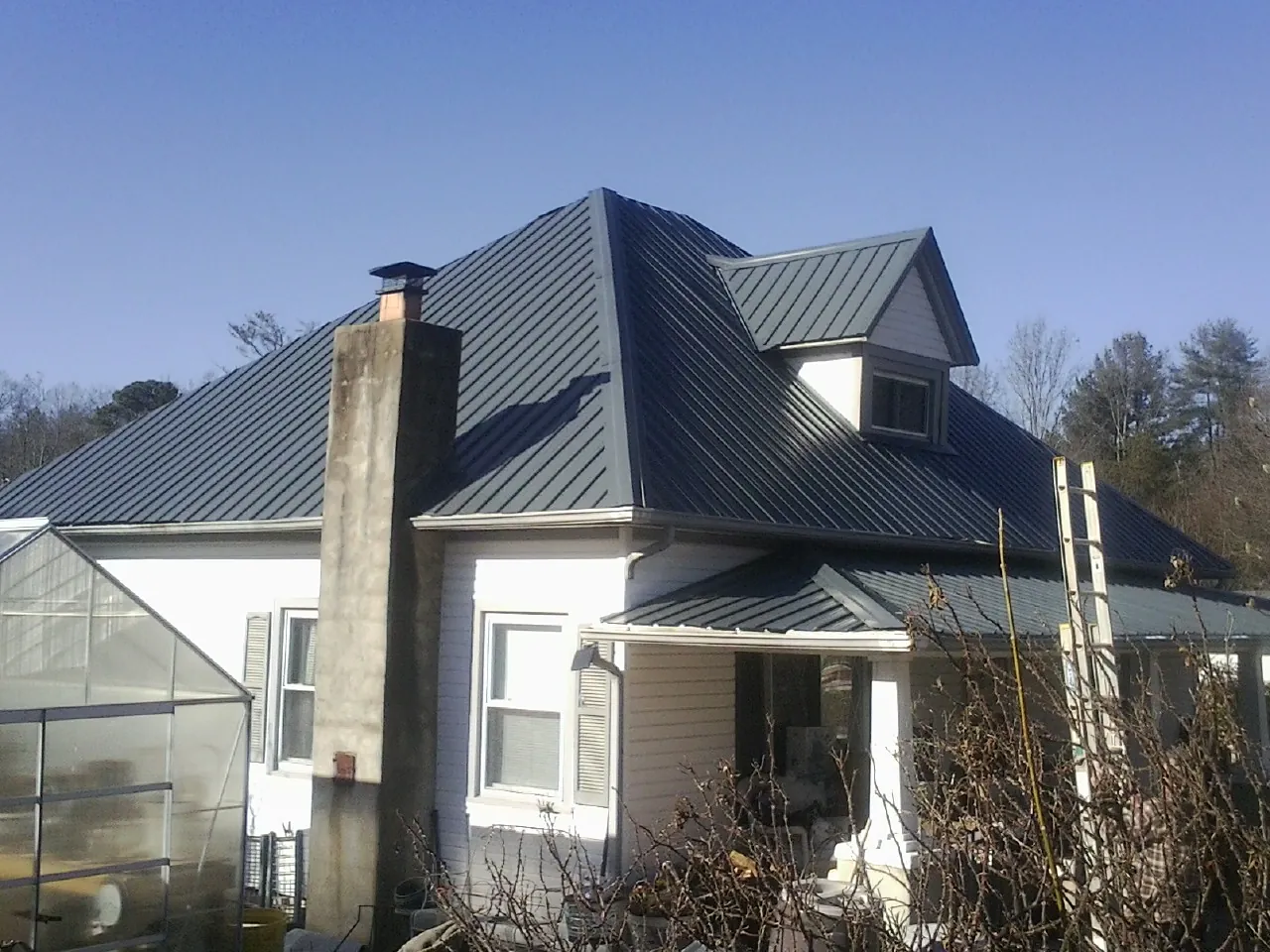 Dark blue standing seam metal roof on a white farmhouse with dormer — Slate & Tile Roof Repair by Roofing Brothers in Moclips