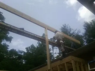Carpenter setting a ridge beam over a new addition frame — Ice Dam Removal by Roofing Brothers in Moclips