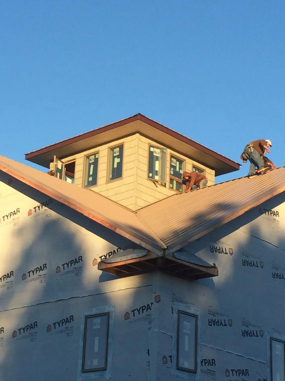 Roofers working around a rooftop cupola on a new metal roof at sunset — Roof Waterproofing in Moclips by Roofing Brothers